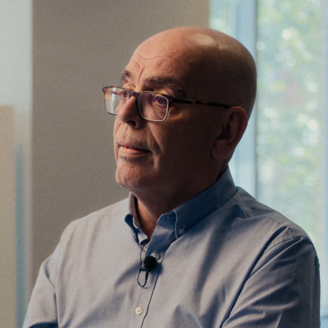 Portrait of Ben Casey wearing glasses and a light blue shirt, seated indoors and looking slightly to his left.